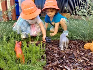 two toddlers playing miniature jungle animals