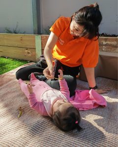 Early learning teacher playing with a smiling toddler