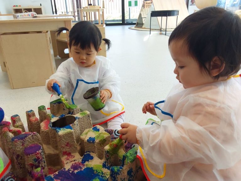 Group of toddlers painting with brushes and bright colours during a creative activity session.